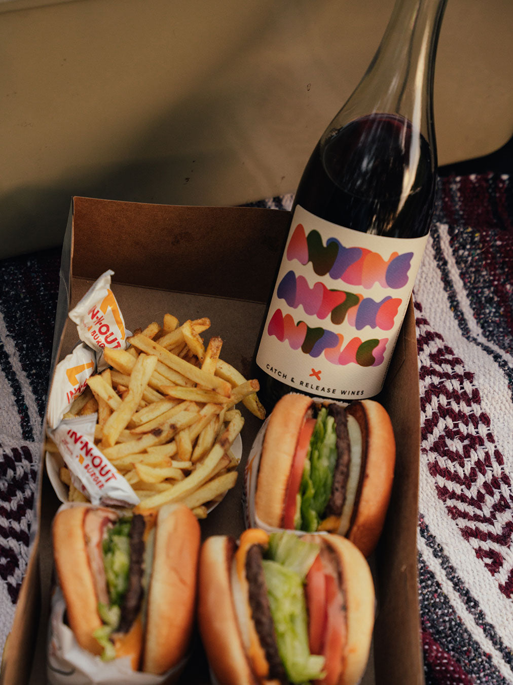 Bottle of Catch & Release Wines Anyone Anytime Anyplace red blend, with in-and-out burgers and fries