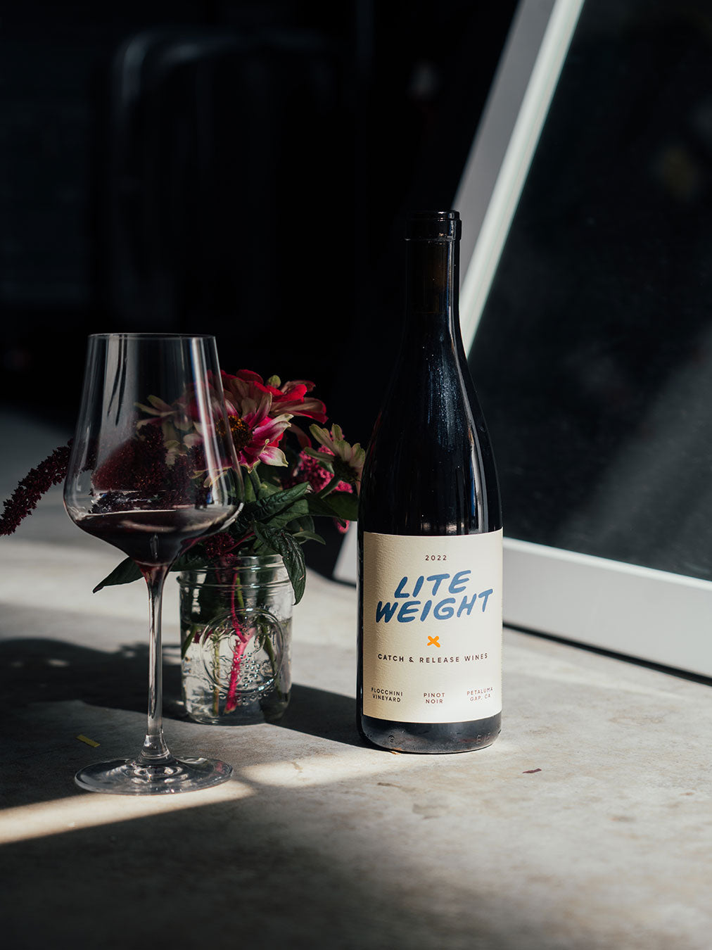 Catch & Release Wines 2022 Lite Weight on concrete with flowers and poured glass