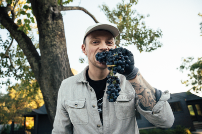 Beno of Catch & Release Wines in the vineyard biting into organic grapes