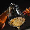 Close-up of a glass with Catch & Release Middle Child wine and a flower on a dark background