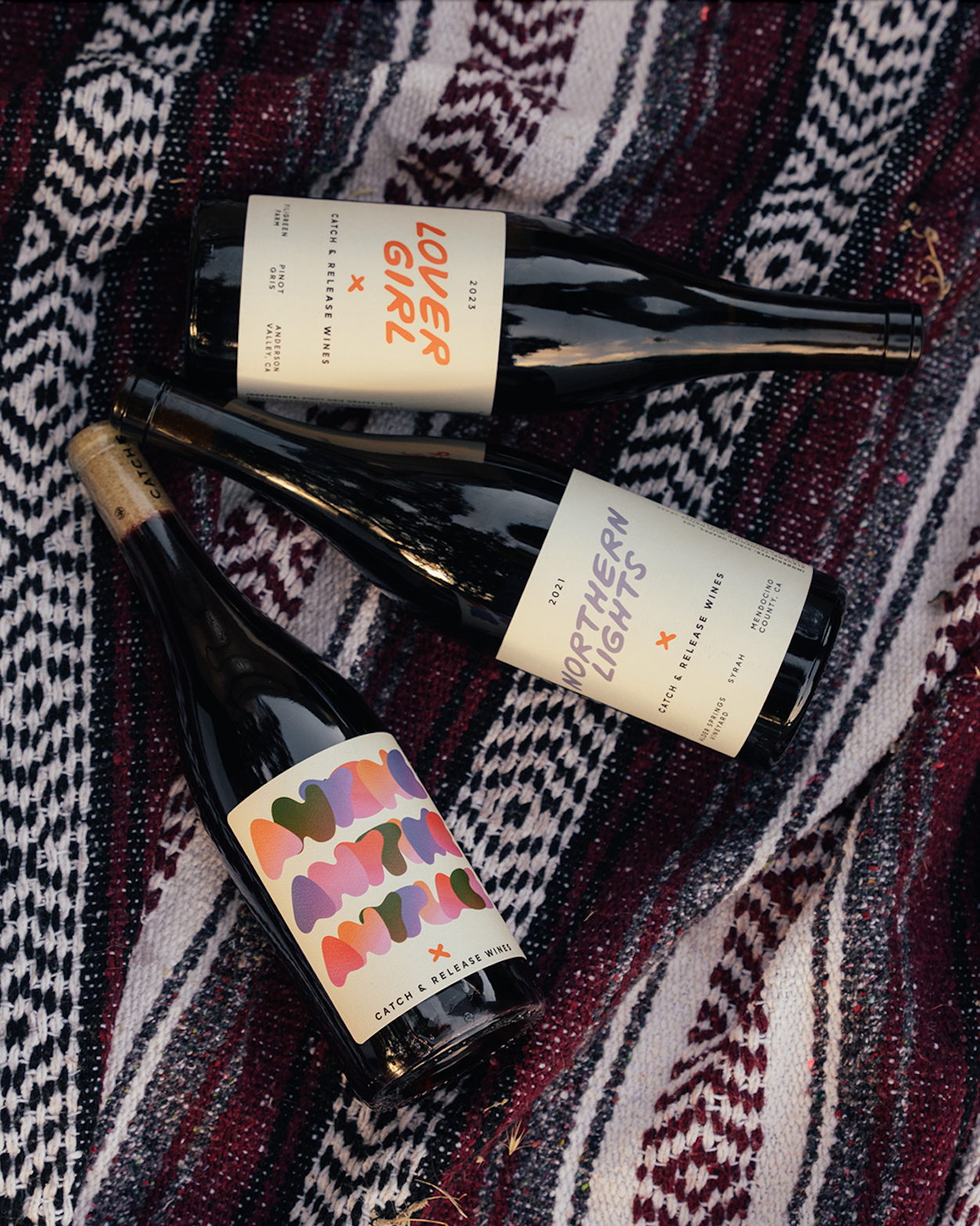 Catch & Release Natural Wines Lover Girl Pinot Gris, Anyone Anytime Anyplace Red Blend, Northern Lights Syrah bottle shots at picnic.