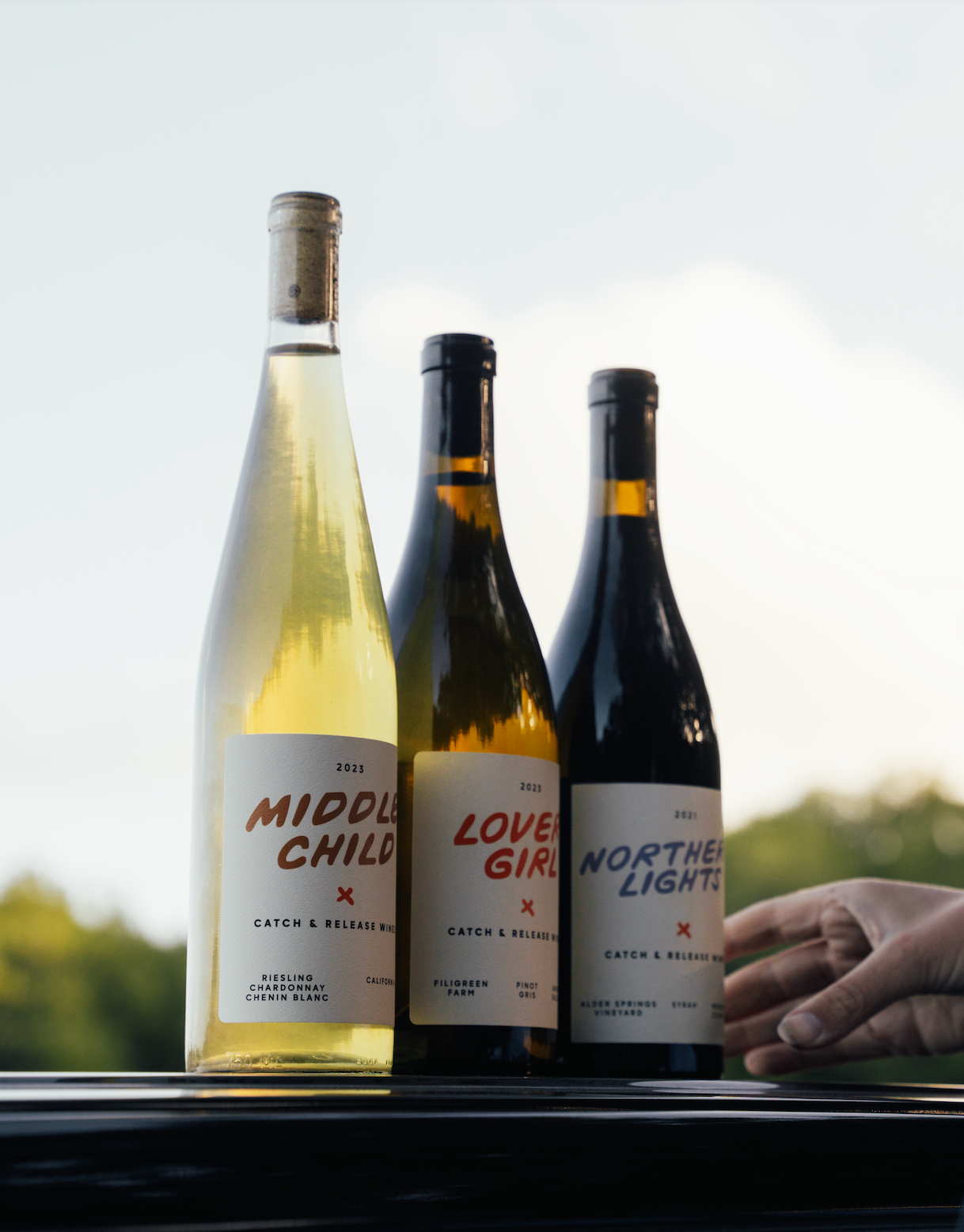 Catch & Release Natural California Wines vineyard shot with skin-contact Riesling Middle Child, Pinot Gris Lover Girl, and Syrah Northern Lights bottles.